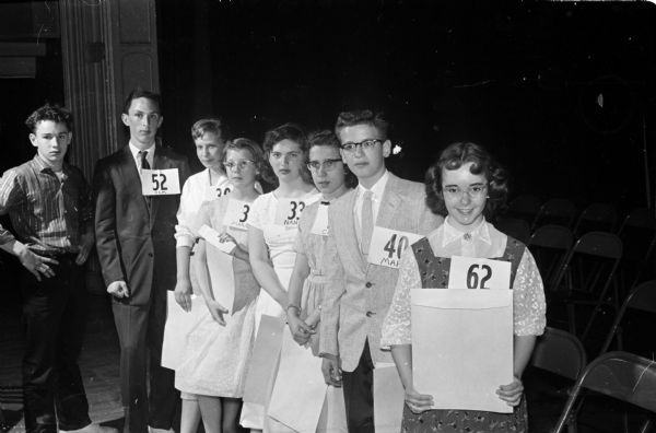 Group portrait of the eight finalists in the 1958 Badger State Spelling Bee. All of them received prizes. Shown, left to right, are: Eddie Thompson, Elroy, eighth place; Jim Myers, Columbus, seventh place; Ann Wegner, West Dane County, third place; Margit Moses, Crawford County, fourth place; Nancy Mueller, Winnebago County, fifth place; Carol Jean Beightol, Green County, sixth place; Marc Williamson, Madison East Junior High, second place; and Carol Fellows, Walworth County, first place.