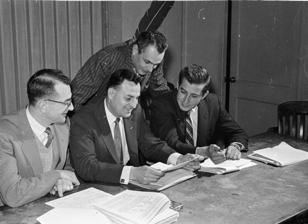 Three representatives of the Child Guidance Center prepare their 1959 budget request at a budget conference. They are, from left to right: Frederick Hinickle, Harold Frye, and Dr. Land Reeck. Henry H. Bush Jr., United Community Chest budget committee member, stands behind them.