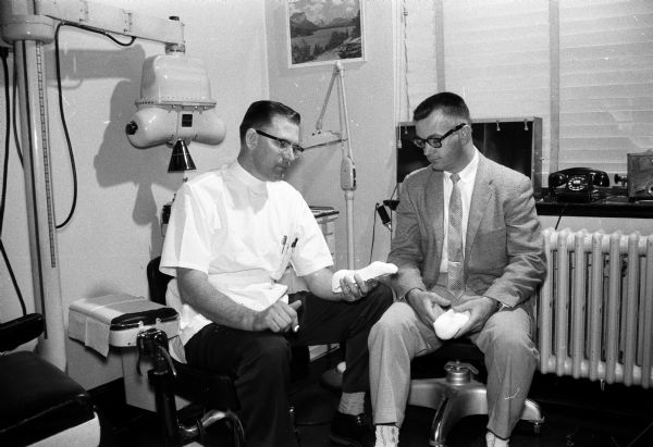 The original caption states: "Two Madison chiropodists, Dr. F.J. Jasensky, left, and R.W. Harmon, right, examine some of the equipment and material used in their profession, podiatry, the treatment of ailments of the feet. The men are among the members of the American Podiatry Association and the Wisconsin Society of Chiropodists which are observing national foot health week."