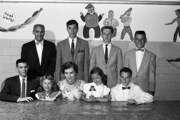 Coaches, team captains and mascots attend the 18th annual Frank Allis School Fathers and Sons Athletic Banquet. Standing in the back row are Coach Les Wozney, Duane Johnson, Wayne Felland, and Tim Cloutier.  Seated in the front row, left to right, are Assistant Coach Irv Kennedy, Carol Brandt, girls' physical education director Opal Winters, Kathy Cloutier, and Ron Howe. "The cute little misses, Brandt and Cloutier, were 'mascot' cheerleaders for the school."