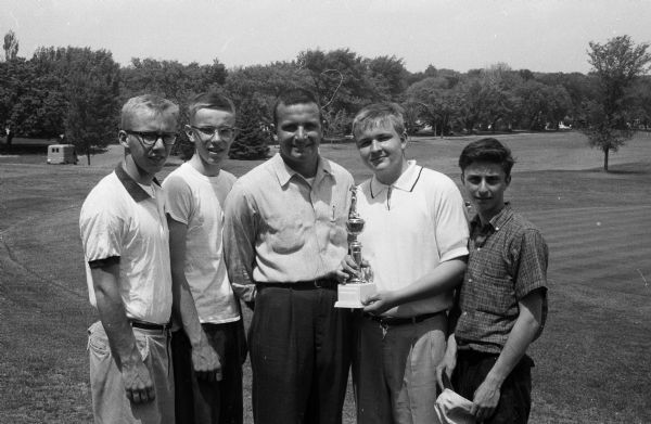 The original caption states, "The Kenosha team that won the Big Eight Conference golf championship at the Nakoma Club is shown. Left to right are Tom LaDousa, Richard Adamson, Coach Joe Brittelli, Mickey Franklin, and Chuck Rizzo."