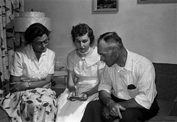 Mr. and Mrs. Kurt Hentschel of Verona look at wedding pictures of their foster daughter, Betty, who lived with them for five years before her marriage to Richard Dahlen. Left to right: Mrs. Hentschel, Betty Dahlen, Kurt Hentschel.