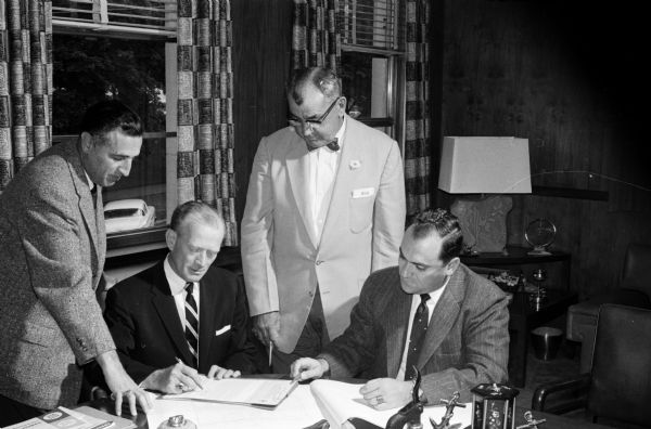 Paperwork is completed for Northland Manor Development Corporation to open an affiliate in Madison. Left to right: William Pessin (Milwaukee builder); Arthur Levin, president of Northland Manor; Al Steinhauer, president of Anchor Savings and Loan; and Sheldon Cohen, secretary of the Northland firm.