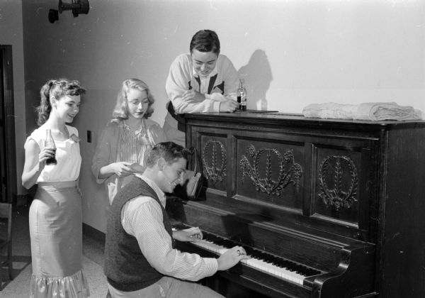 The original caption reads: "Having fun around the piano; played by Tom Heine; are, left to right, Tara Auringer, Jane Ogden, and leaning in above the piano, Jeff Kravat. They'll be amoung the youths acting in and doing technical work for children's plays at playgrounds this summer."