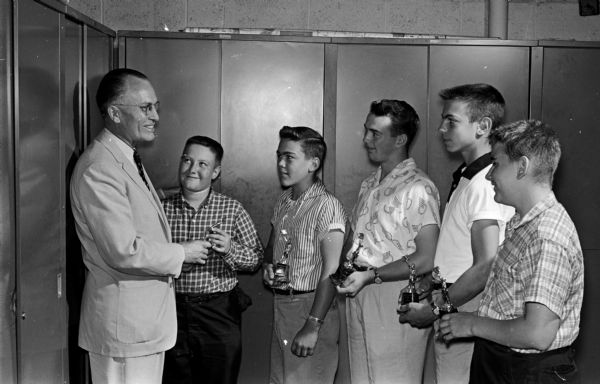 John Canny, left, circulation manager for Madison Newspapers, Inc., presents trophies to five of the Wisconsin State Journal's most efficient carrier salesmen (paperboys) in recognition "for all-around good work in delivering newspapers, collecting and building up routes." With trophies in hand, they are, left to right: Jerry Nelson, Dan Keller, James Halpin, Clary Olmstead Jr., and William Sauk.
