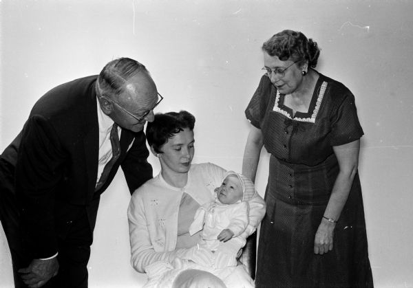 Infant Michael Scott Hanmer (center) is held by his mother Betty. He is the mascot for a special Red Cross blood drive because Michael and his mother received blood transfusions after his birth. Standing nearby is George D. Goodearle, left, and Lucille Flanagan. They are both members of the Gallon Club.