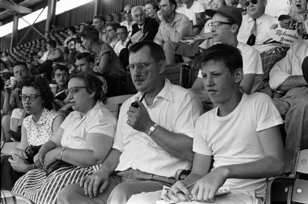 Joan Boeker (left), and Julia and Glarice Pierce with their newspaper carrier son, LeRoy, watching the Milwaukee Brave's game at a stadium.