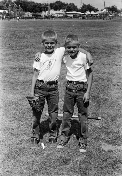 Richard "Ricky" and Michael "Mickey" Schepp, ten-year-old twin sons of Charles and Matilda Schepp, pose with their arms around each other's shoulders at a baseball game. Mickey had had surgery to correct a heart defect and is now able to participate in sports along with his brother Ricky.