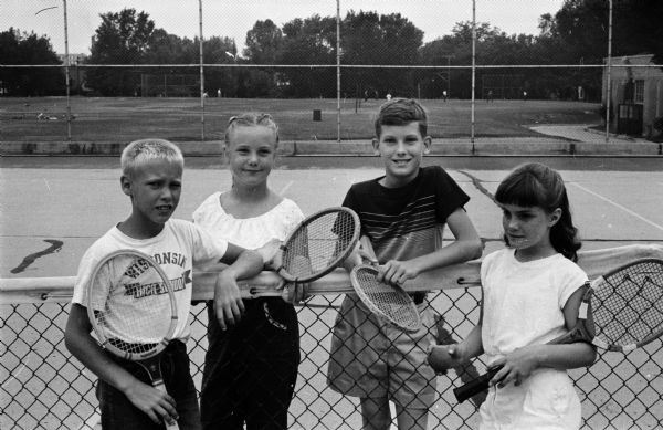 Youngsters take break during a practice session for the 1958 city closed tennis tournament. Left to right: Dick Dubielzig, Mary Ellen Bohl, Ray Rideout, and Peggy Stafford.