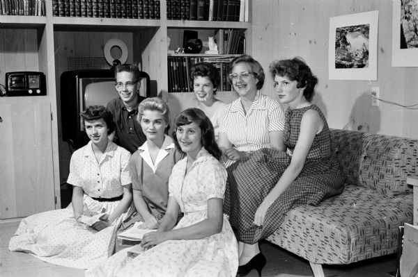 Group portrait of seven members of a committee planning an upcoming dancing party sponsored by the Westmorland Association. Front row, left to right, are: Joanne Lillywhite, decorations; Jackie Plenke, general chairman; Leilani Wessels, music. Back row: David Stedman, publicity; Judy Herbert, refreshments; Betty Bergmann, tickets; and Mary Walsh, prizes.