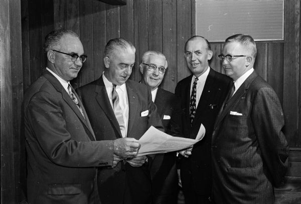 Some 30 Madison members of the Amalgamated Lithographers of America Union received their own chapter after being members of a Milwaukee local for two years. Shown from left to right, looking over the new local document, are: Herman Wagner, new local 92 president; George Canary, International president; Oliver Mertz, International vice-president; Norman Simon, local 7 Milwaukee president; and Leon Wichersham, International representative.