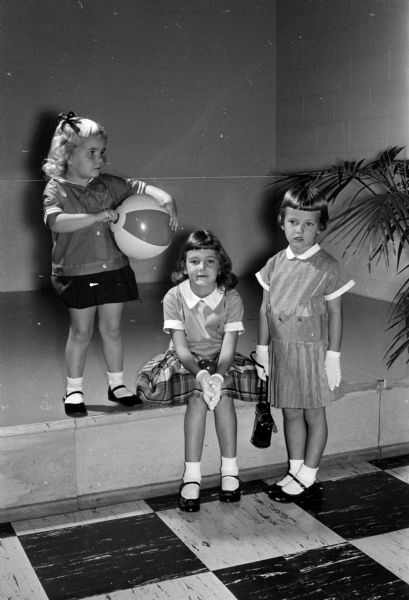Three young girls, children of members of the East Side Women's club, model at a style show presented at a meeting of the club. Pictured from left to right are: Patty McMahon, Lori Lindau, and Linda Johnson.