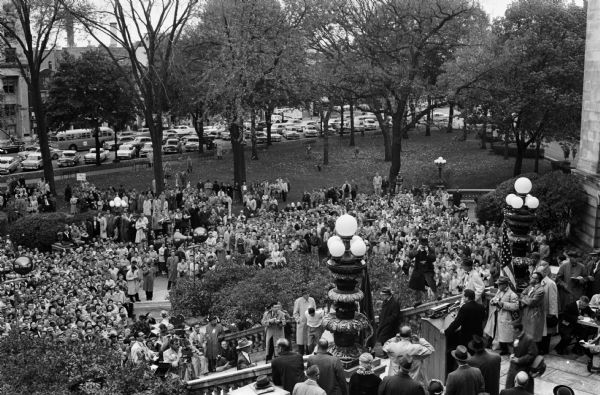 Elevated view of a crowd of nearly 3,000 people gathered at the Capitol Square to hear Vice-President Richard Nixon speak. The vice-president is visible standing at a podium at the extreme lower right.   
