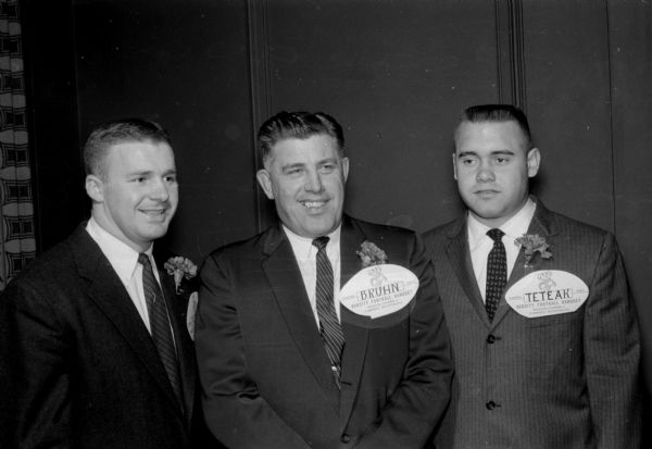 Milt Bruhn, center, Wisconsin football coach, and his most valuable players of 1958 are pictured at the banquet. At the left is fullback Joh Hobbs; at right is center Darel Teteak.