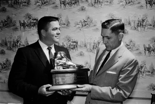 Members of the National Sales Executive Club of Madison were hosts to their bosses at "Top Management" Night. Highlight of the evening was the presentation of a bronzed shoe for "tireless footwork" to Arlie Mucks, Jr., left, secretary of the club. The presentation was made by Harry E. Manzer Jr., past president of the club.