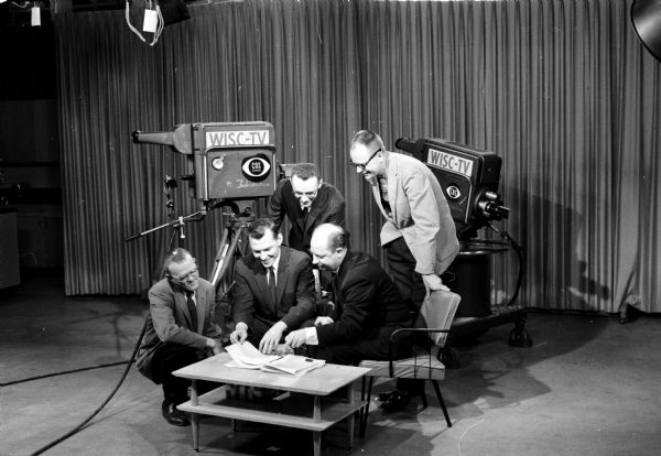 Behind-the-scenes workers at WISC-TV make preliminary plans for the Empty Stocking Christmas show. Front row, left to right, Walter Harlu, technical director; Dan Imhoff, program director and Jerry Bassett, producer. In the back row are Tom Bass, assistant producer and Burd Myre, director.