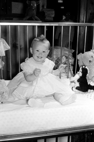 Linda Lee Elverman, 19 month-old daughter of Mr. and Mrs. Sheldon Elverman, sits in a crib at Morningside Sanatorium where she is recovering from tuberculosis.