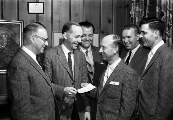 A check for $400 is being handed over to the State Department of Public Welfare by the Associated Optimists Clubs to help in a study of "hard-to-reach youth" in Madison. Front row are, left to right: Joseph Werner, chairman of the Madison Commission for Youth; Bjarne Romnes, supervisor with the State Department of Public Welfare; C.J. Klingele, president of the associated clubs; and Bernard Strumbras, graduate student making the study. In the back row are, left to right: Ernest Goranson, consultant with the public welfare department and Robert Voss, president of the West Madison Optimists Club.