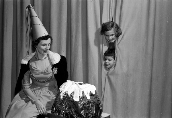 Nakoma's Twelfth Night Party features the historical pageantry of the Twelfth Night tradition. Admiring a giant-sized "plum pudding" were Marjorie Davenport, dressed as an Elizabethan lady-in-waiting, and two pages. Julie Leonard is at the top and Susie Noyce is below.