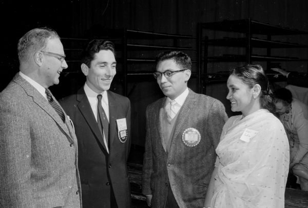 Madison Rotary Club members honored 150 foreign students attending the University of Wisconsin at a "fiesta" at the University of Wisconsin Stock Pavilion. Joseph Werner, district governor of Rotary International, chats with foreign students, left to right, Yilmaz G. Belentepe, Turkey; Rosendo Sanchez, Mexico; and Laxmi Bulusu, India.