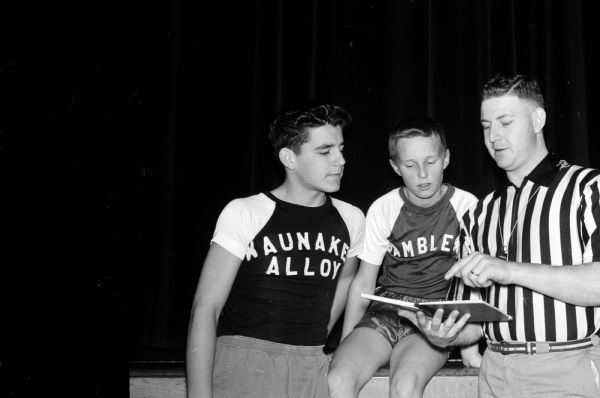 Eddie Hellenbrand, right, goes over the box score of a Waunakee youth basketball league game with players Frank Miller and Steve Heyn. Eddie administers the program.