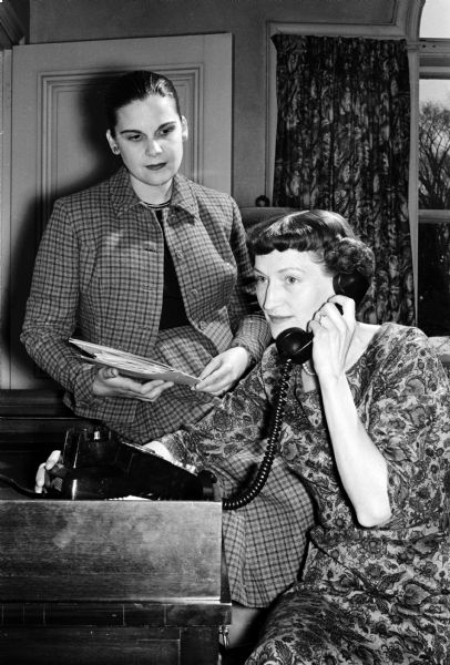 Mrs. Gaylord Nelson, wife of the governor and honorary chairman of the Dane County mental health campaign, places one of the first telephone calls to recruit workers for the house-to-house drive to be held on May 11, 1959. Assisting Mrs. Nelson is Mrs. Herschel Leibowitz, campaign committee chairman.