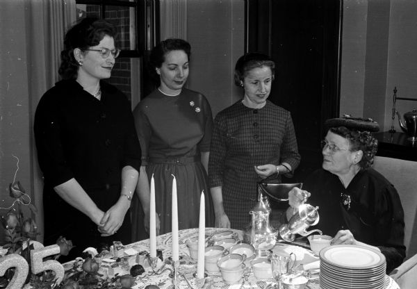 Mrs. Samuel Burns, seated, serves tea after the Sigma Alpha Iota Benefit Musicale to (left to right): Shirley Dominik, Elizabeth Rennebohm, and Mrs. Fred Marsh.