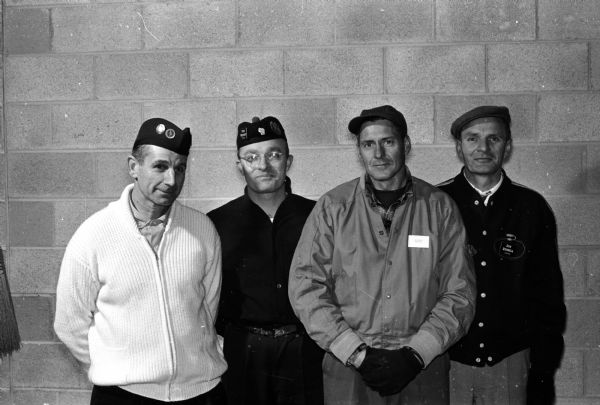 Group portrait of four men wearing tams and berets on their heads. The original caption states: "The Don Russell rink of Pardeeville won the Madison Curling Club invitational bonspiel by scoring its fifth straight victory in the 32-rink event. Left to right are John Schneider, lead; Dr. Stan Wescott, second; Bob Baillies, third; and Don Russell, skip."