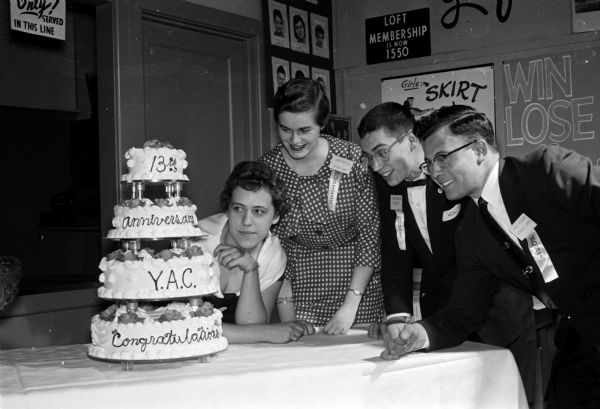 The 13th anniversary of the Madison Young Adult Club is celebrated at a party at the Madison Community Center, 16 E. Doty Street. Shown admiring a fancy cake (left to right) are Gerri Femrite; Jean Butler, secretary; Larry Brown, president; and LeRoy Kroeger, club activity chairman.