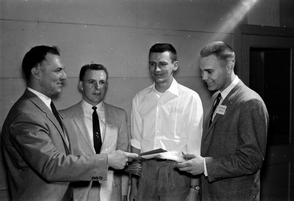 The 13th anniversary of the Madison Young Adult Club is celebrated at a party held at the Madison Community Center, 16 E. Doty Street. The evening's festivities included the presentation of awards to winners of the game room tournaments and the dance contest competitions. Shown presenting an award to (right) Robert Haukedahl is (left) Gene Wendland, club advisor. Watching are (left to right) Felix Wildgruber and Al Moschkau.