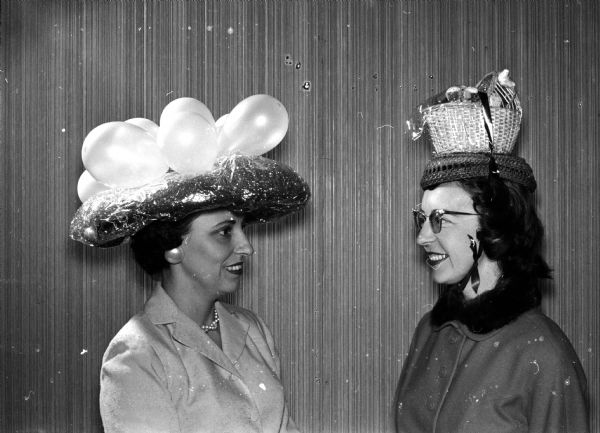 Original colorful hats of all types and designs appeared at the spring "Mad Hat" luncheon at the Blackhawk Country Club. Mary Feifarek, left, wears a hat featuring green Easter grass in a cellophane nest with balloons representing Easter eggs. Arliss Nelson has two straw baskets perched on her head. The top one, a straw doll bassinet, is filled with Easter candies and novelties.