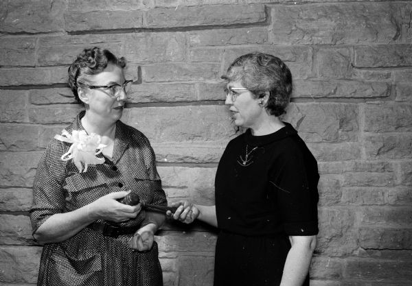 Outgoing president of the Madison League of Women Voters, Mrs. Beatrice Lampert, hands over the gavel to the incoming president, Mrs. Katherine Lichter. The local convention was held at the Unitarian Meeting House.