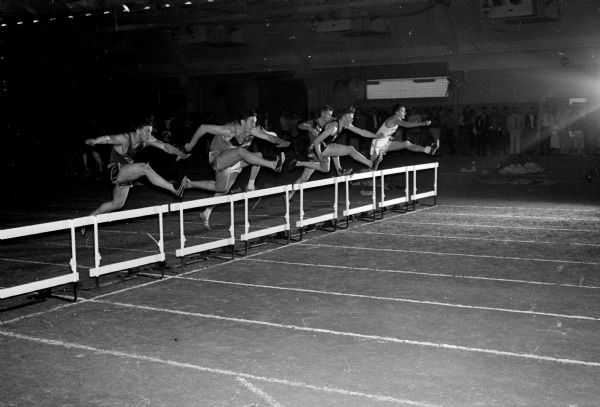 Runners clear hurdles in the Class B 70-yard low hurdles during the Madison West Relays at the Camp Randall Memorial building. The winner was Karl Hecker of Plymouth (second from left).