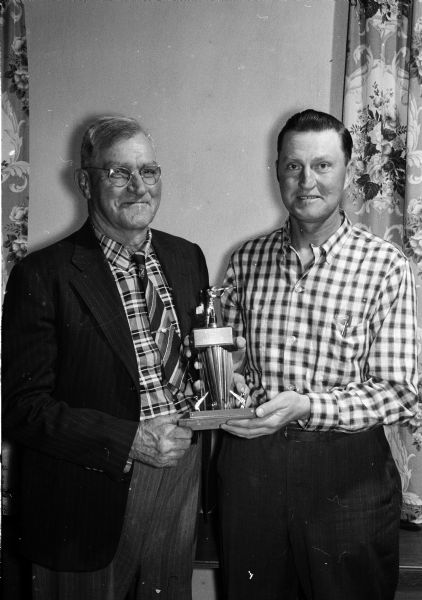 Veteran marksman Forrest Henderson, left, of Mt. Horeb, accepts the Southwestern Wisconsin Rifle League championship trophy for the Mt. Horeb rifle team from league secretary Elmer Schult, Belmont.