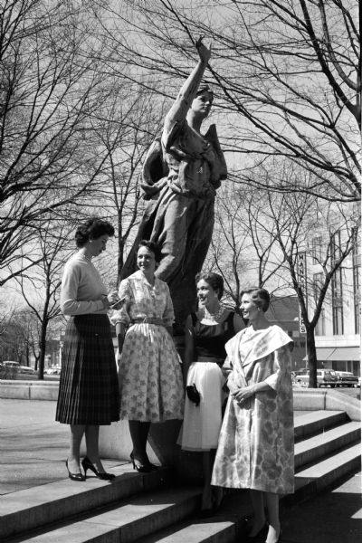 Members attending the Panhellenic Alumnae dessert, style show and bridge benefit at Nakoma Country Club. Attendees include, from left to right: Marylu Rauschenbush (publicity chairman), and three models for the style show: Mary Sylvan, Donna Bartel, and Emma Sorum. They are standing in front of the Forward statue on the Capitol Square.