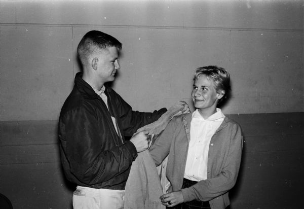 George Schlotthauer helps his date, Carol Rusch, with her coat before going to a movie. The photograph was taken for a series of photos themed, "What To Do On A Date."