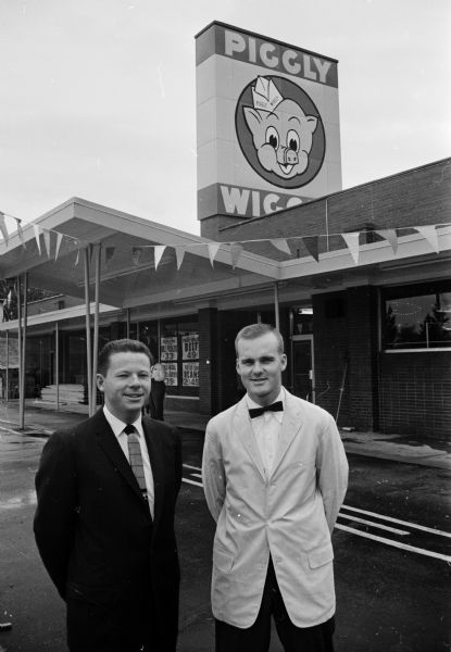 Two men are posing in front of a new Piggly Wiggly grocery store. The new store was located in Middleton at the intersection of Gateway Street and University Avenue. The men were William Thomas, store manager, and Charles Pember, assistant manager.