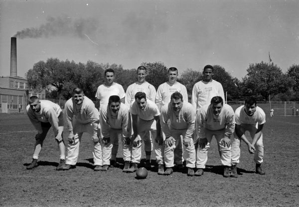 Varsity team offensive lineup for the annual University of Wisconsin Alumni-Varsity football game at Camp Randall Stadium. In front, left to right, are: Dave Howard, John Dittrich, Paul Shwalko, Gary Messner, Norm Amundsen, Dave Suminski, and Norbert Esser. In back, left to right, are: Earl (Jug) Girard, John Dixon, Jim Haluska, and Danny Lewis. Elroy (Crazy Legs) Hirsch was not present for the picture.