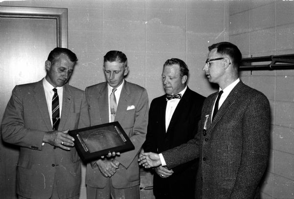Edward Schultz, left, director of the Wisconsin Policeman's Protective Association and Ft. Atkinson police chief is shown presenting a "meritorious service award" to three Madison policemen for their handling of an east side Madison man who was armed with a shotgun. The three men, left to right, are Kenneth Kalhagen, Ray Crary and Francis Trapp.