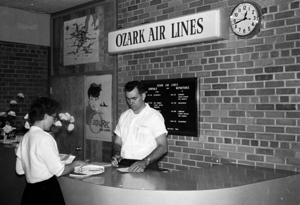 Stanley Cobane, manager for Ozark Air Lines, stands at the service desk with his wife Joyce Cobane. Ozark Air Lines was the third airline to provide service at the Madison airport.