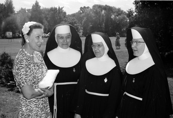 Bishop William P. O'Connor hosts more than a thousand guests & members of the Madison Diocesan Council of Catholic Women and their families at a chicken barbecue dinner at his home on the shore of Lake Mendota. Shown (left to right) are Mrs. Merrald Haag, president of the council and general chairman of the gathering; Sister Dorothea O.S.F.; Sister Eucharista, O.S.F.; and Sister Michael Marie, O.S.F.