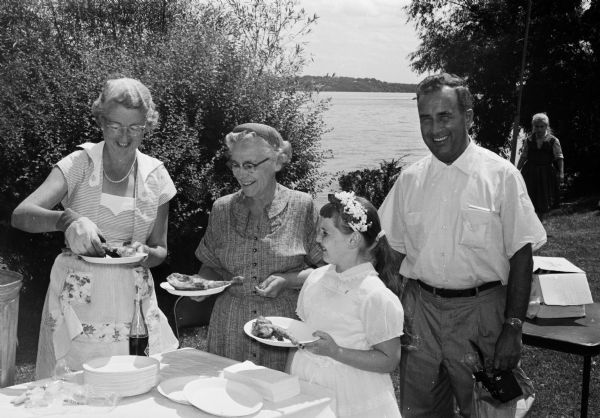 Bishop William P. O'Connor hosts more than one thousand guests and members of the Madison Diocesan Council of Catholic Women and their families for a chicken barbecue dinner at his home on the shore of Lake Mendota. Shown (left to right) are Mrs. Joseph Capaul, chairman of the food committee; Mrs. A.J. Falter; Christine Falter; and George Hickey.
