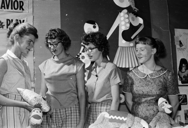 A new home economics class for girls at the 1959 Dane County Junior Fair is called "Let's Care for Children." Looking over an entry are (left to right) Eloise Yelk, Janet Dollak, Joann Dollak, and Donna Weisensel, all from Marshall, and members of the Sun Prairie 4-H Club.