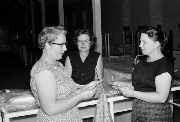 The 1959 Dane County Junior Fair home economics building is the center for 1,000s of entries made by girls of Dane County in the clothing and food categories. Shown checking in the entries are (left to right) home economics superintendents Mrs. August Baumann, Rt. 1, Cottage Grove; Mrs. Roy Amidon, Rt. 1, Brooklyn; and Mrs Robert Renk, Rt. 2, Sun Prairie.