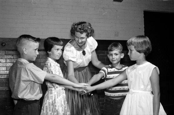 Four square dancing youngsters learn the "star" movement under the guidance of Mrs John (Ruth) White, 118 Shepard Terrace. Left to right are James Reilly, 2410 Center Avenue; Jane Hewitt, 309 Karen Court; Mrs. white; Carl Landsness, 230 Waubesa Street; and Jane Akerman, Ann Arbor, Michigan, a friend of Miss Hewitt.