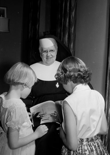 Group portrait of Sister Mary Anastasia and two young girls at St. Colleta's School for Exceptional Children in Jefferson, Wisconsin. Sister Mary Anastasia has been working as a teacher with children who had various forms of mental disabilities for fifty years and as the school's supervisor since 1925. The school had 500 children from all over the world at the time of the photograph, with a waiting list of 500 more.