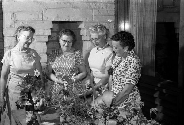 Members of the Little Garden Club admire some experimental arrangements for their flower show. Members include, from left, Verna Custer, Ann Collentine, Stella Angell,and Mary Havey.