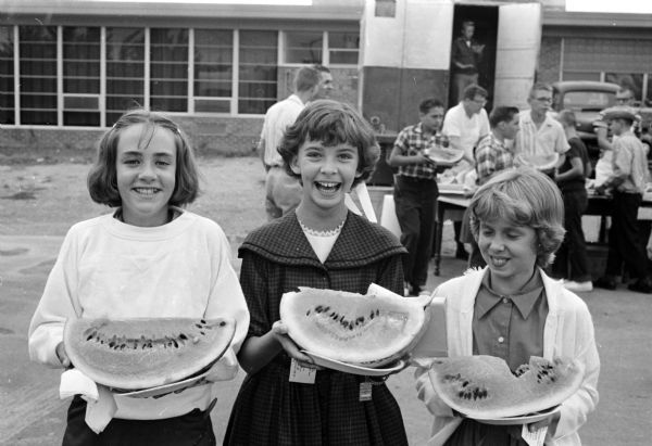 Children enjoying big slices of watermelon at the Monona Grove Businessmen's Association watermelon festival. They include, from left, Kay Marks, Dannie DuBois, and Debora Lindauer.