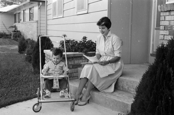Mrs. Robert (Rita) Collins, 4602 Waterman Way, ticket chairman for the East side area of the Jaycettes, auxiliary to the Madison Junior Chamber of Commerce, is busy with details of their annual benefit fashion show.  Her son, Mark, age 1 1/2 years, is in the stroller.