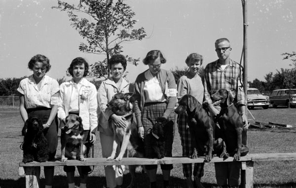 Six participants in the all-breed obedience trails sponsored by the Lakeland Dog Training Club in Cambridge posing with their dogs. Left to right are Janice McFarlane of Lake Mills with a Cocker Spaniel, Jeannie Martin of Lake Mills with a Beagle, Maxijne Vaage of Stoughton with a German Shepherd, Marjorie Mueller of Jefferson with a Poodle, Mrs. Kenneth Gerstner of Cambridge with a Weimaraner, and Kenneth Gerstner with a Weimaraner.